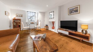 Un salon comprenant un canapé, une table basse, un téléviseur, une bibliothèque et un coin repas avec des chaises et une table.