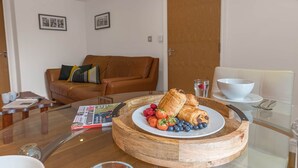 Une table de petit-déjeuner avec des viennoiseries, des fruits rouges et un magazine, le tout disposé sur une planche en bois.