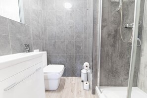 Une salle de bain moderne équipée d’une douche, de toilettes et d’un lavabo.
