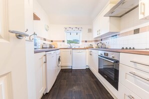 A compact kitchen with a dishwasher, oven, and a window with a view. - Felltops, 6 Lonsdale House, Elliott Park (Keswick)