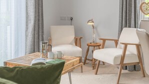 Een moderne woonkamer met een bank, fauteuils, een salontafel en een lamp.