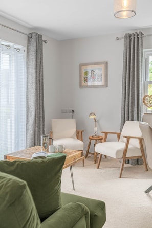 Ein modernes Wohnzimmer mit einer Couch, Sesseln, einem Couchtisch und einer Lampe.