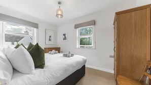 Een slaapkamer met een groot bed, een houten garderobe en een raam met uitzicht.