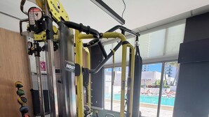 Gimnasio con una estación de levantamiento de pesas, un neumático grande y vistas a una piscina exterior.