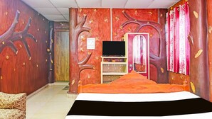 A bedroom with a bed, a TV, a wardrobe, and a door. - Deluxe Ranihati Tripureswari (Howrah)