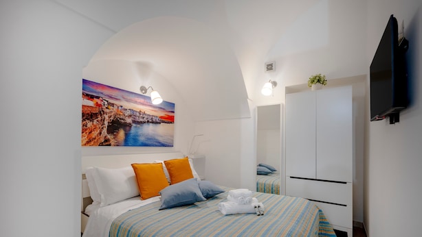 Ein Schlafzimmer mit Bett, Kissen, einem Gemälde, einem Kleiderschrank und einem Fernseher.