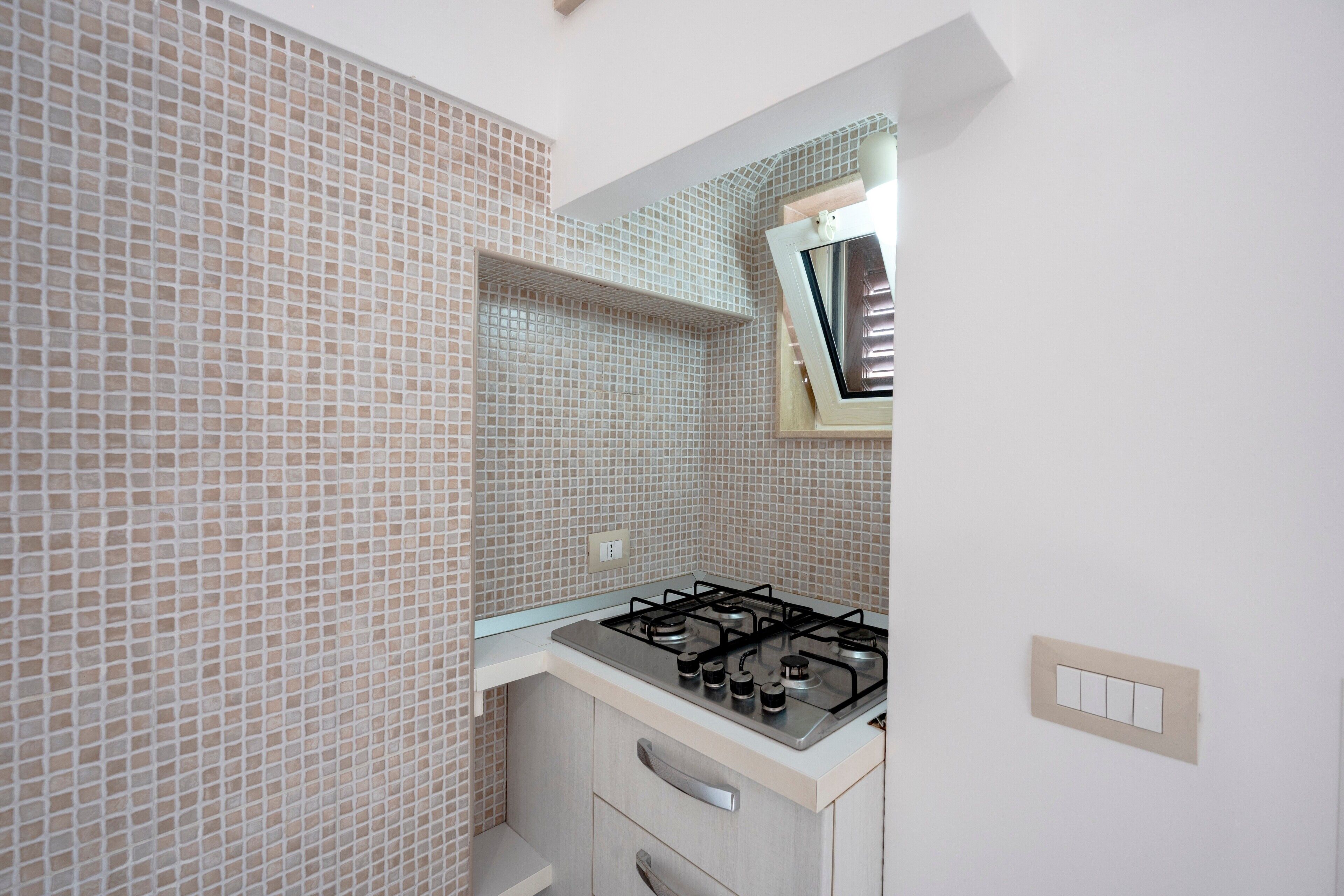 Uma cozinha com fogão a gás, uma janela e painel de azulejos.