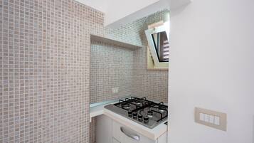 Uma cozinha com fogão a gás, uma janela e painel de azulejos.