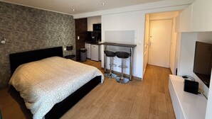 Een slaapkamer met een bed, een kleine kitchenette en een televisie.