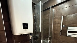 Een moderne badkamer met toilet, douche en wastafel.