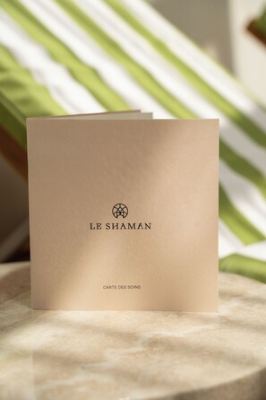 A beige card with 'LE SHAMAN' and 'CARTE DES SOINS' text, placed on a marble surface. - Château du Portereau (Vertou)