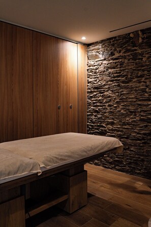 A bedroom with a bed, wooden wardrobe, and a stone wall. - Château du Portereau (Vertou)
