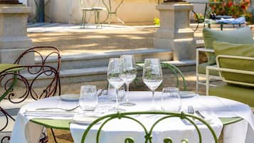 An outdoor dining area with a table set for four, surrounded by green metal chairs.