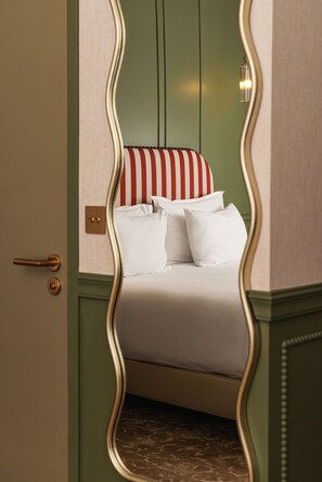 A bed with white bedding and striped pillows, a green wall, and a door with a brass handle. - Château du Portereau (Vertou)