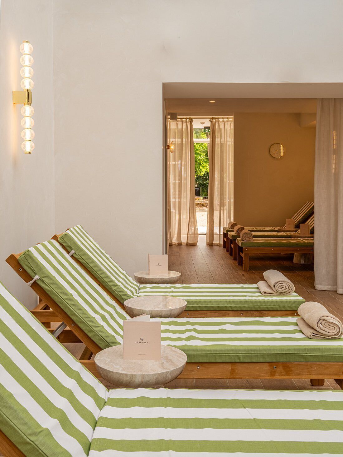 A spa area with multiple lounge chairs, a reception desk, and a view of the outdoors.
