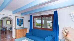 Ein Zimmer mit einem blauen Sofa, einem Holzkasten und einem Tisch mit einem Papier.