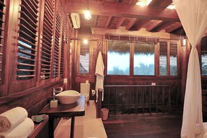 A wooden bathroom with a large window, a sink, and a towel rack. - Casa Kundavi Hotel (Villa de Tututepec de Melchor Ocampo)