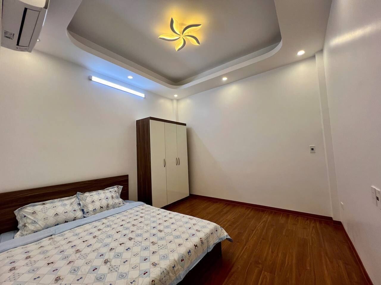 A bedroom with a bed, wardrobe, and a ceiling light fixture.