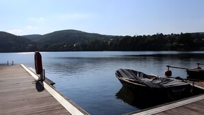 Eine Holzsteg, der sich in ruhiges Wasser erstreckt, mit einem Boot, das zur Rechten abgedeckt ist.
