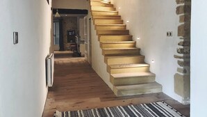 A staircase with wooden steps leading to a landing, a stone wall on the right, and a hallway with a radiator and a rug. - Luxury Secluded Chateau With Pool and hot tub (Beynac-et-Cazenac)