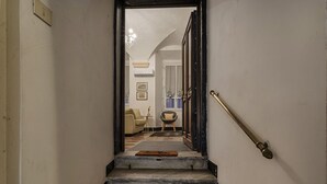Een trap die leidt naar een kamer met een kroonluchter, een bank en een bijzettafeltje.