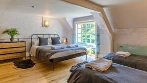 A bedroom with a loft-style ceiling, a bed with a headboard, a dresser, a window with a view, and a plant. - Entire Victorian Schoolhouse With hot tub and Harbour Views (Fowey)