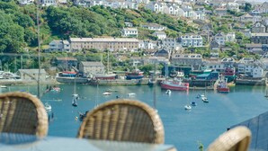 A harbor with boats, a chair, and a table. - Entire Victorian Schoolhouse With hot tub and Harbour Views (Fowey)