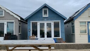 A beachside building with a blue facade, large windows, and a visible door. - Stargaze From a Beach hut on the Mudeford Sandbank (Bournemouth)