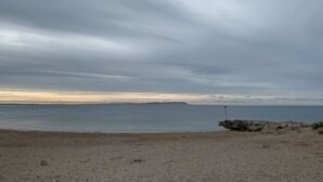 A beach with a cloudy sky, calm water, and a distant shoreline. - Stargaze From a Beach hut on the Mudeford Sandbank (Bournemouth)