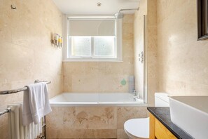 A bathroom with a bathtub, toilet, and a window. - Converted Flat in Amazing Converted Schoolhouse Near Fowey Harbour (Fowey)