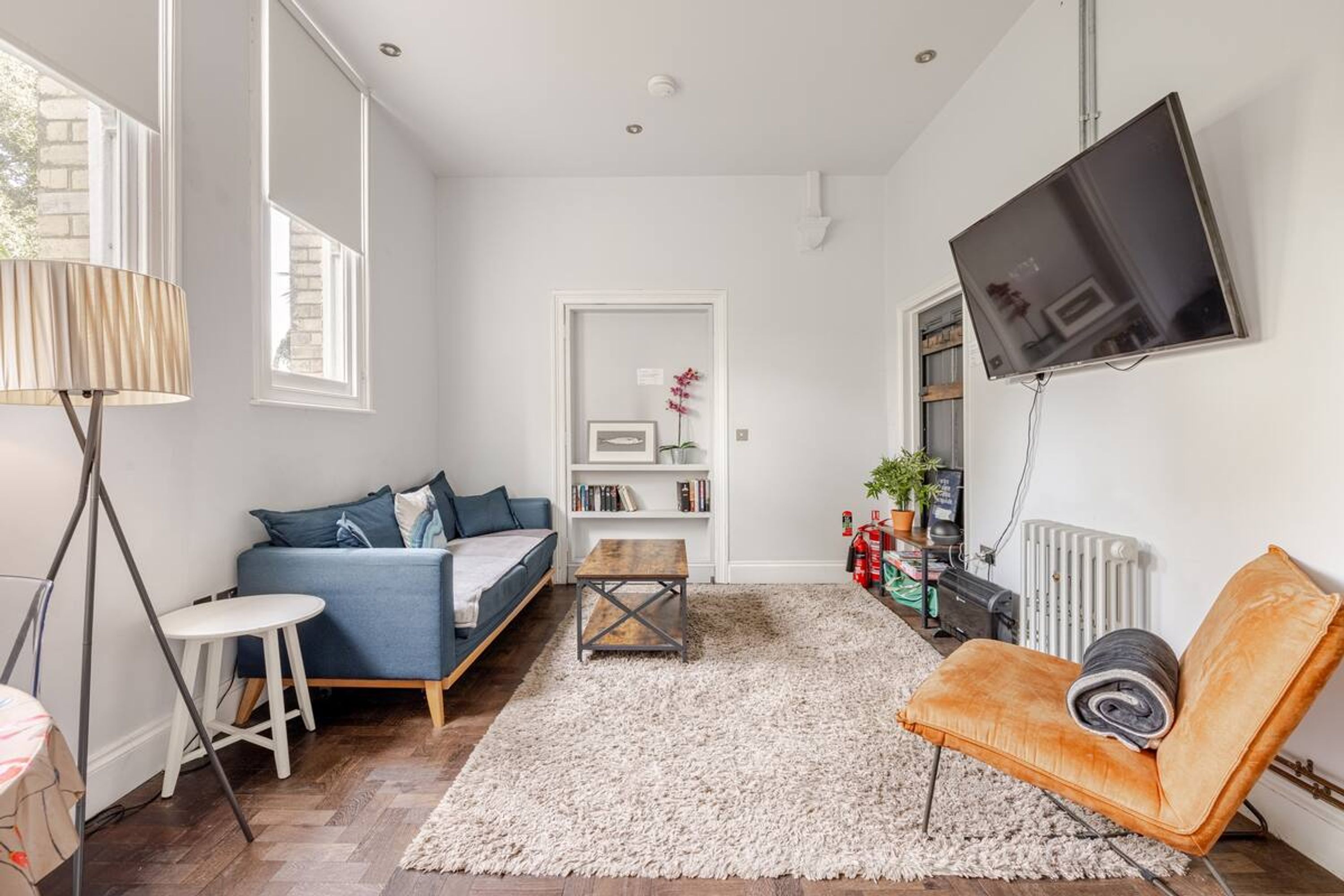 A living room with a sofa, a coffee table, a TV, and a radiator.
