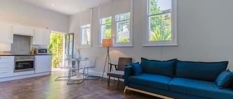 Un grand espace de vie comprenant un canapé, une table à manger avec des chaises et une cuisine à l’arrière-plan.