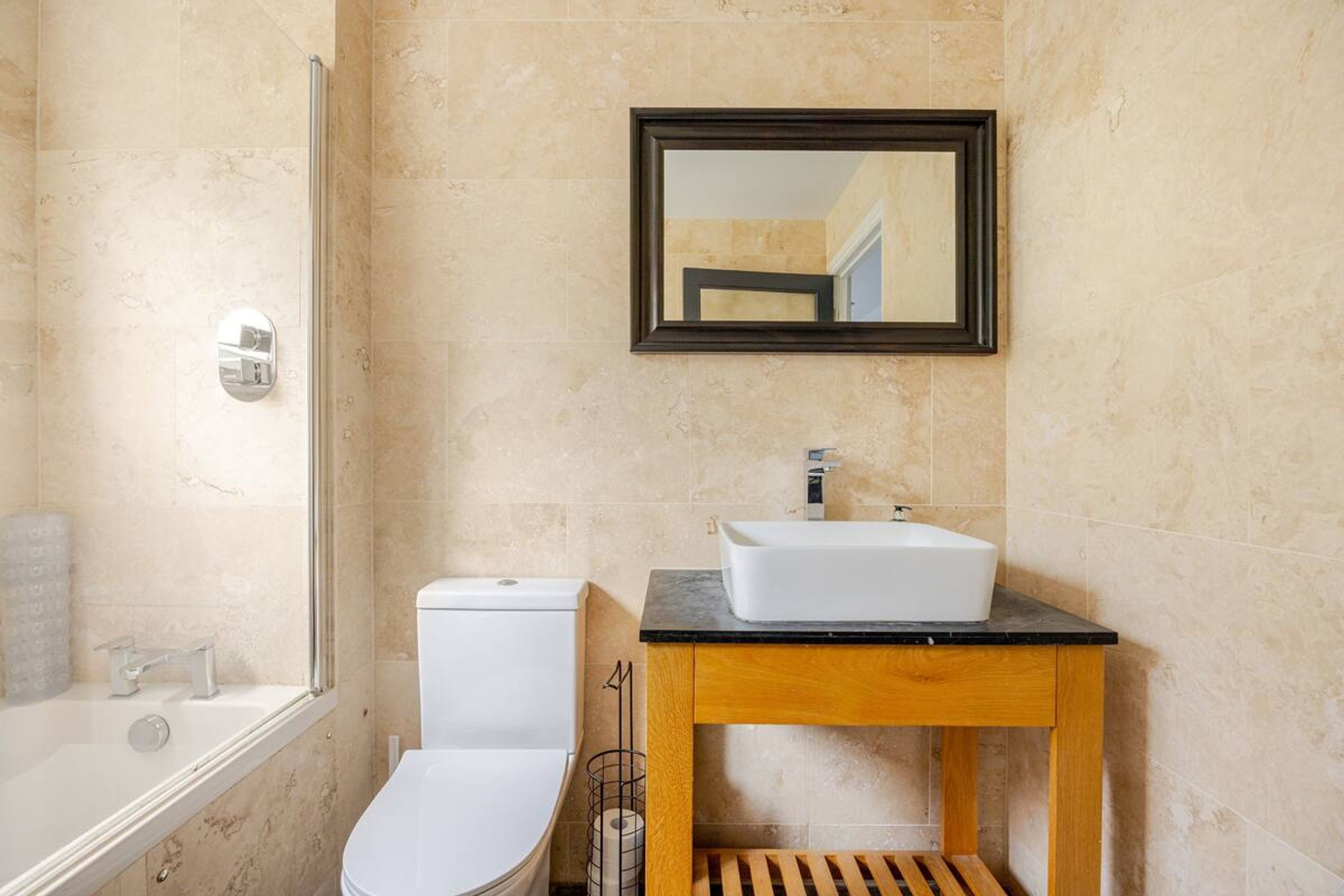 A bathroom with a bathtub, toilet, sink, and a mirror above the sink.