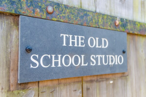 A sign with the text 'THE OLD SCHOOL STUDIO' mounted on a wooden surface. - Charming Summerhouse in Fowey Town Center (Fowey)