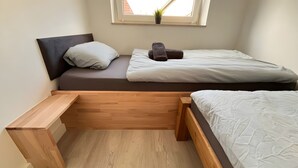 A small, single-bed room with a wooden bench, a potted plant, and a window with a view. - Apartment for 2 People (25 m²) in Kreuzau (Kreuzau)