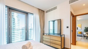 Camera d'albergo con un letto grande, una cassettiera in legno, uno specchio e vista sulla città attraverso un'ampia finestra.