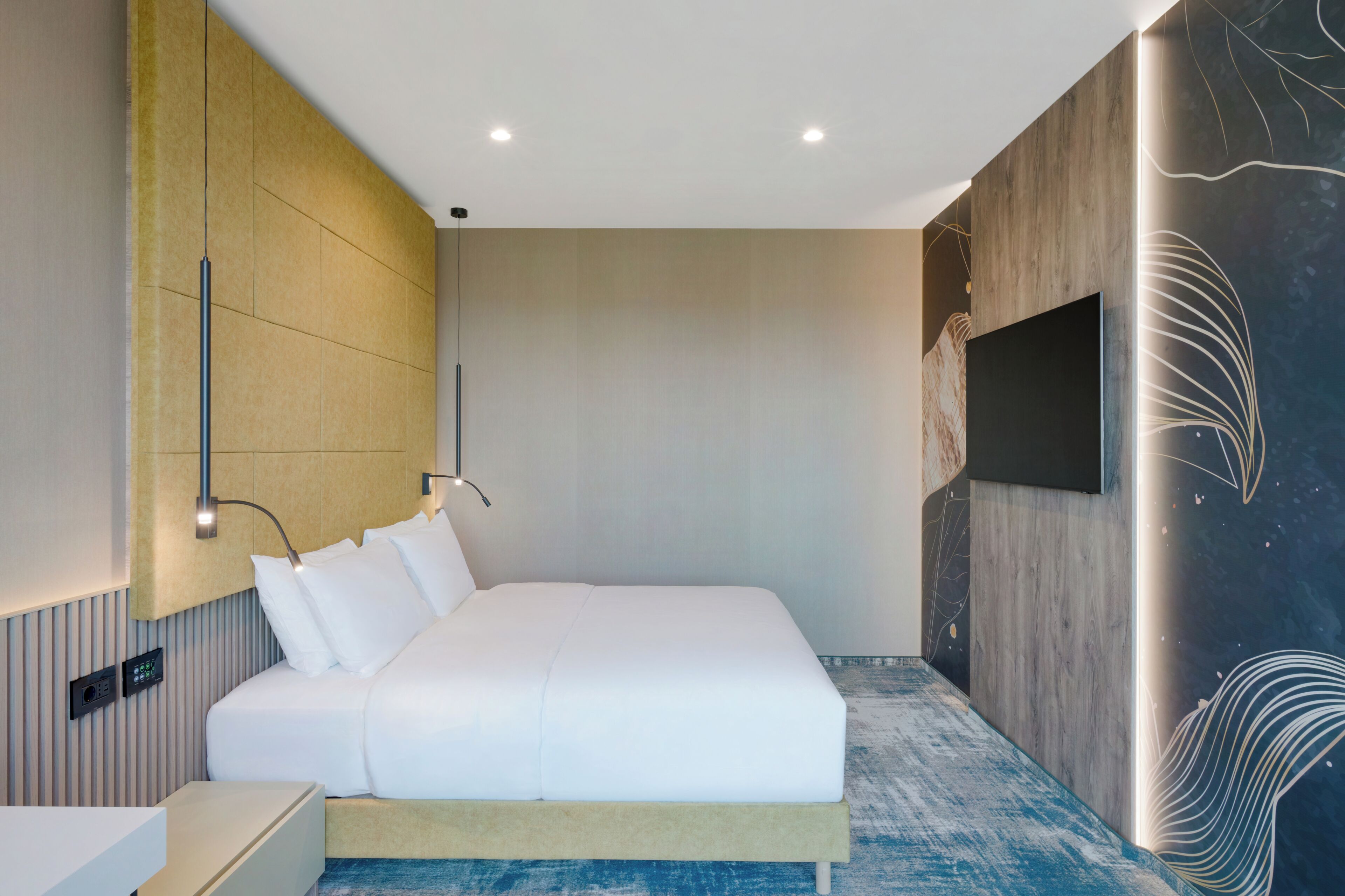 Une chambre d’hôtel moderne dotée d’un grand lit, d’un téléviseur à écran plat, d’une lampe fixée au mur et d’un panneau décoratif mural.