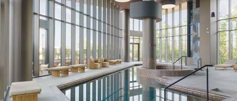 Un área de piscina interior moderna con asientos a lo largo de las paredes y una fuente central.