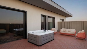 Eine Dachterrasse mit Whirlpool, einer Couch und zwei Stühlen.
