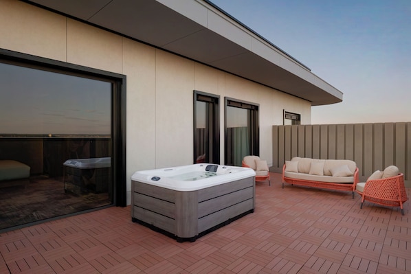 Eine Dachterrasse mit Whirlpool, einer Couch und zwei Stühlen.