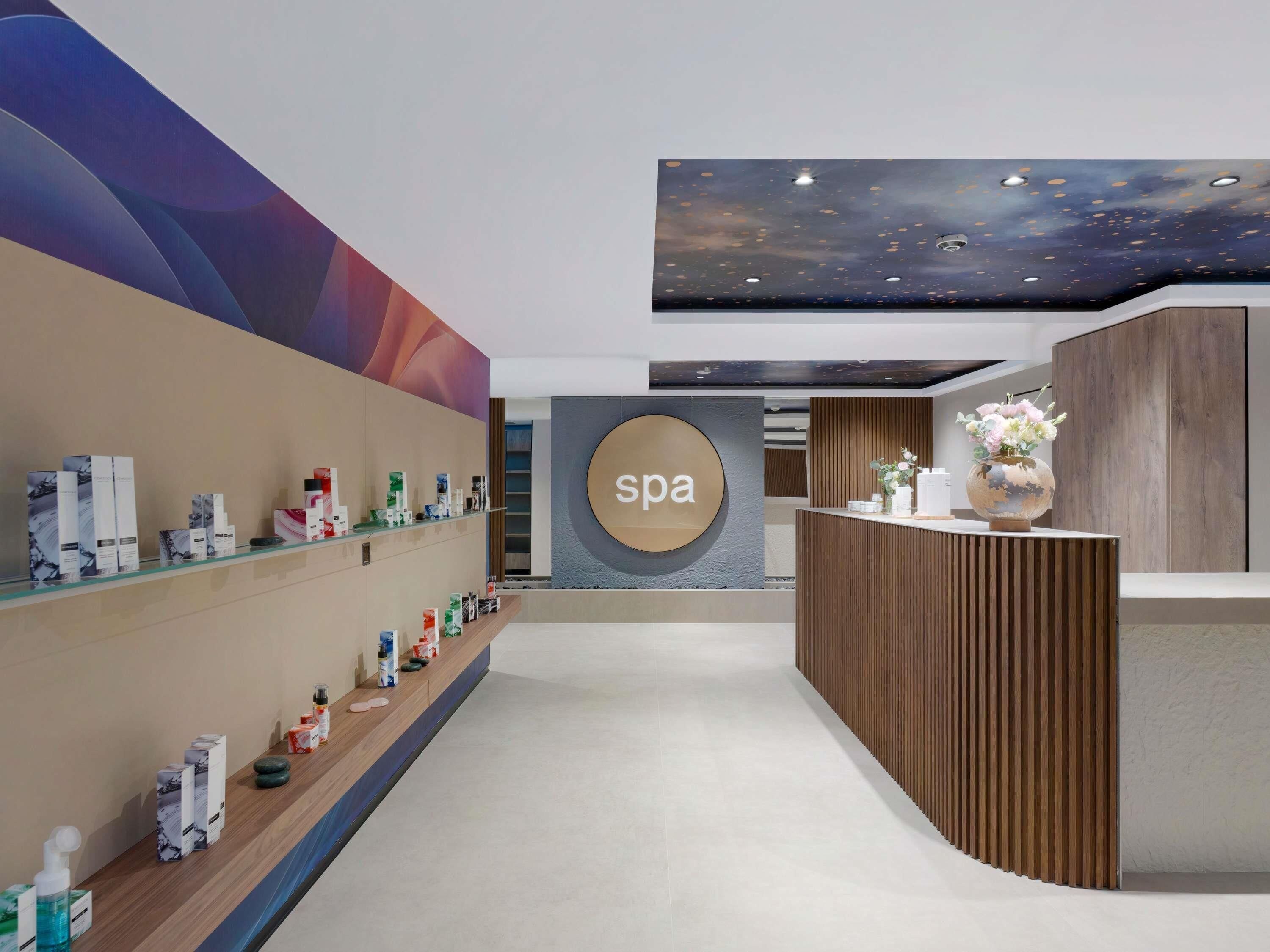 A spa reception area with a 'spa' sign, shelves with toiletries, and a wooden reception desk.