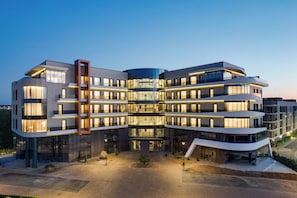 Un hotel de varios pisos con fachada curva, ventanas amplias y un patio central.