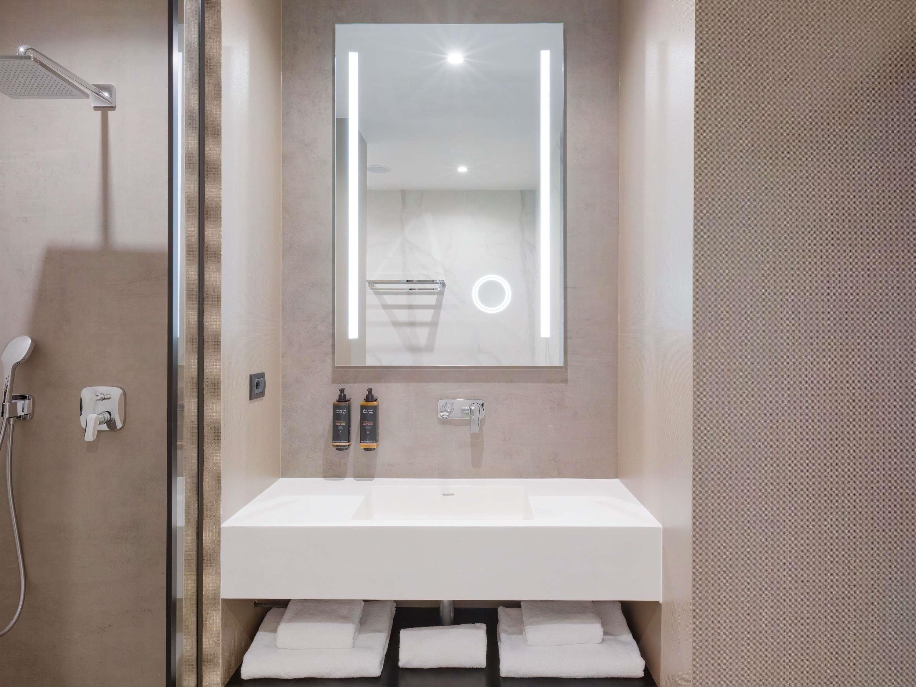 Une salle de bain moderne avec un grand miroir, une douche et un lavabo.