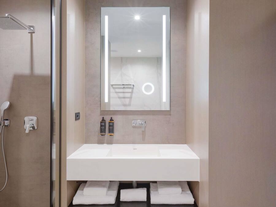 Une salle de bain moderne avec un grand miroir, une douche et un lavabo.