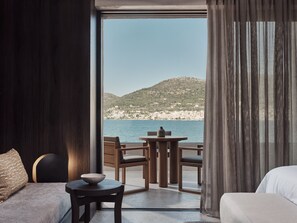 Una habitación con vistas a un paisaje costero, un sofá, una mesa con un cuenco y una silla.