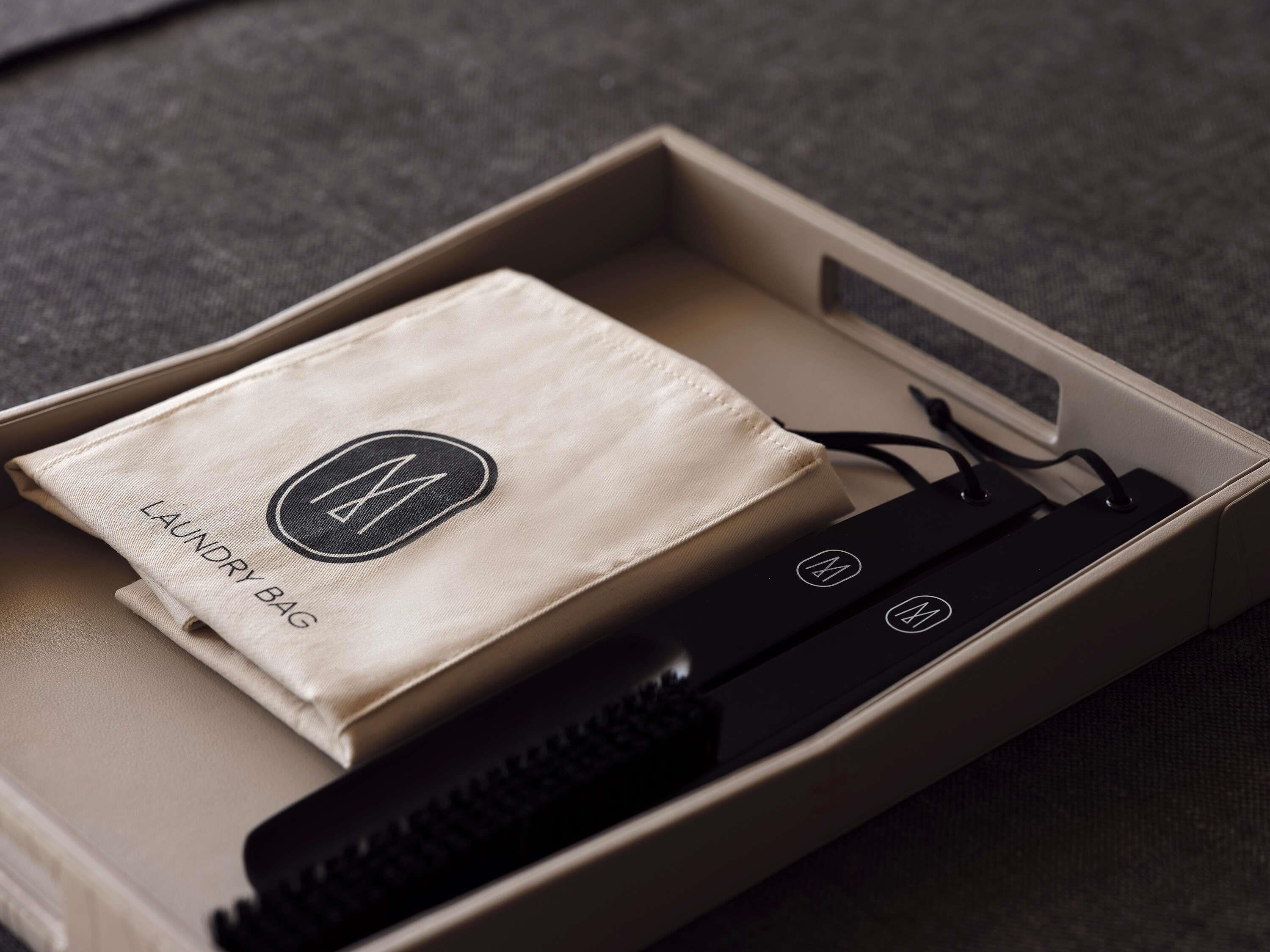 A beige box containing a black portable charger and a beige cloth with a logo.