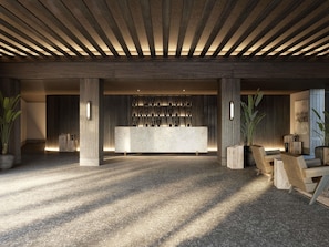 Eine großzügige Lobby mit Empfangstresen, Holzbalken an der Decke und Zimmerpflanzen.