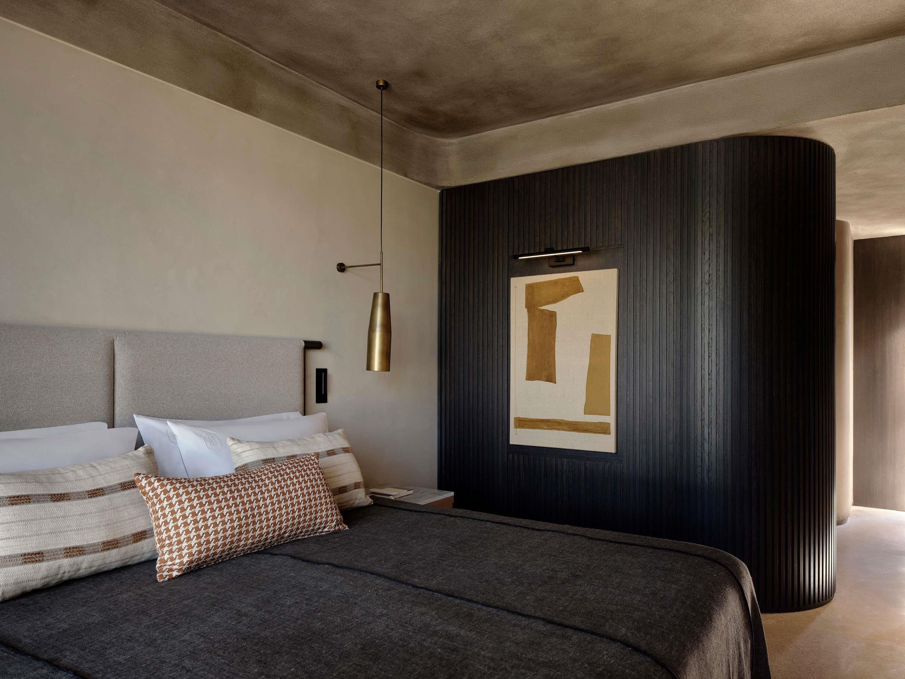 Un dormitorio moderno con una cama grande, un aplique de pared y una obra de arte abstracta única.