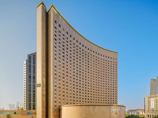 A high-rise hotel with a distinctive curved facade, multiple floors, and a prominent logo. - Swissôtel Living Shanghai Hongqiao (Shanghai)