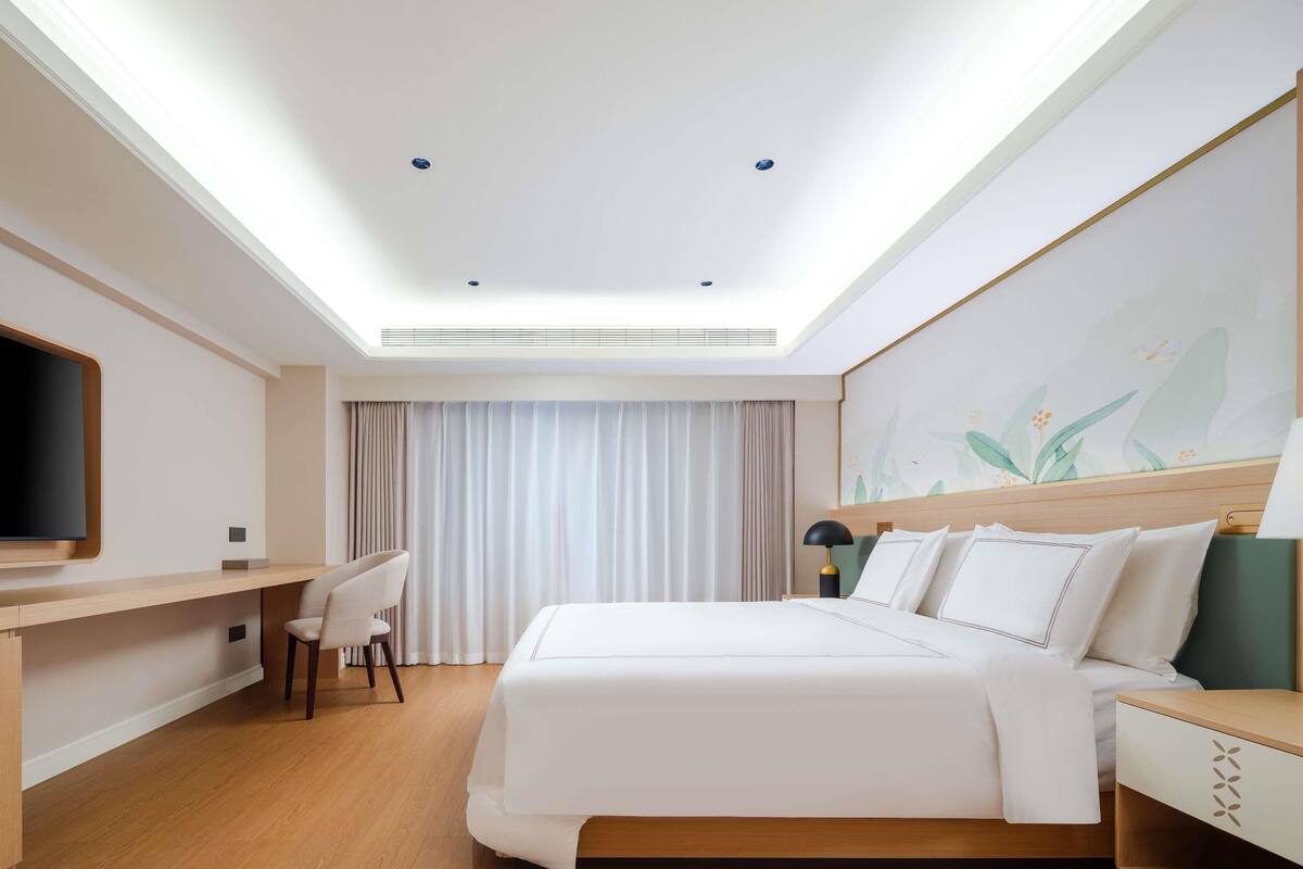 Una camera d'albergo moderna con un letto, una scrivania, una sedia e una TV a schermo piatto.